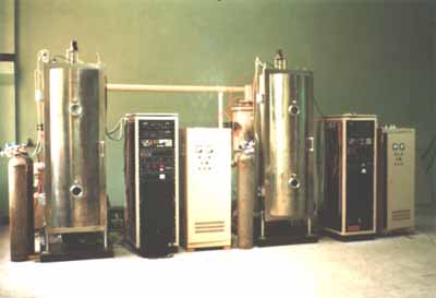 Fig.3. Photograph of two commercial-scale cylindrical DC magnetron sputter coaters, installed in a production line, for depositing Al-N cermet solar coatings onto batches of tubes. The vacuum chamber, 1.9 m high, is on the left. The front door of the chamber is for manual loading of tubes. A DC power supply unit (40A/600V) for sputtering is shown on the right. The control cabinet is in the middle between the chamber and the DC power unit.